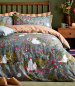 Front view of the Bootanical Forest Halloween duvet cover showing white ghosts amongst colourful pink, orange, purple and white woodland flowers on a blue-grey background, with rust and cream striped bedding.