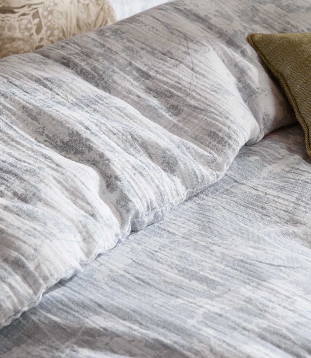 Close-up of Braeflower duvet cover in soft grey by Voyage Maison, showing the delicate botanical design and naturally relaxed muslin texture.