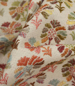 Detailed close-up of Briar Sprig Jasmine woven upholstery fabric featuring colourful floral sprigs in coral, pink, blue, green and ochre tones with textured weave detail.