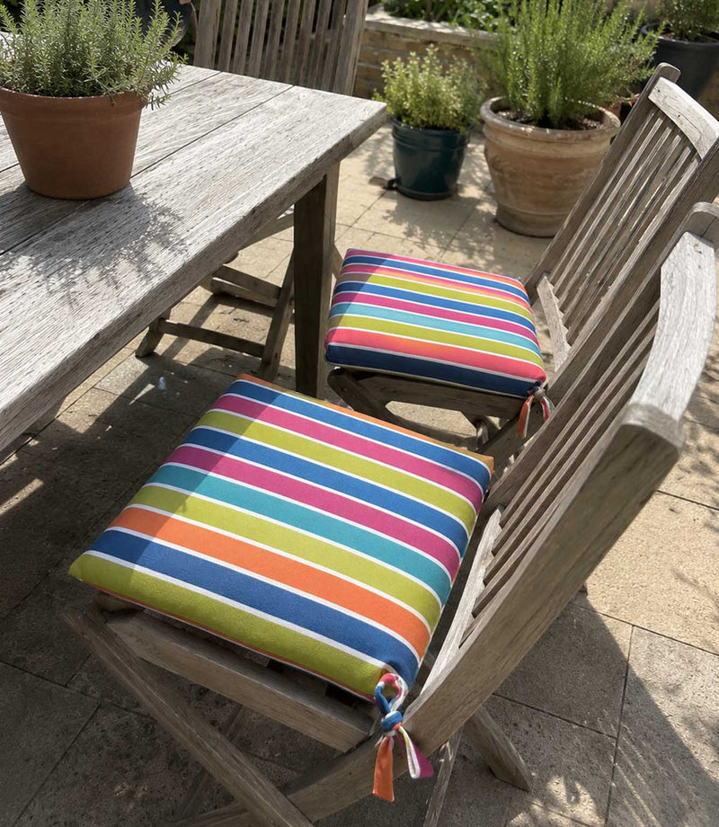 Wooden outdoor chairs with colourful striped fabric cushions on a patio.