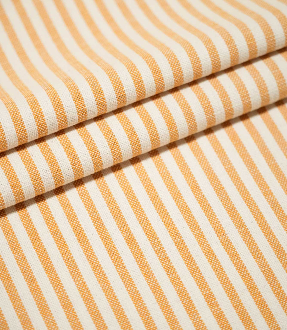 Broadway Stripe Sunflower fabric arranged in three neat overlapping folds, displaying the repeating sunflower orange and off-white striped design and textured weave across both flat and gently curved surfaces.