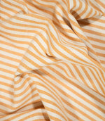 Broadway Stripe Sunflower fabric loosely draped into flowing folds, showing how the regular orange and off-white stripes curve naturally with the movement of the material while retaining their clean, evenly spaced pattern.