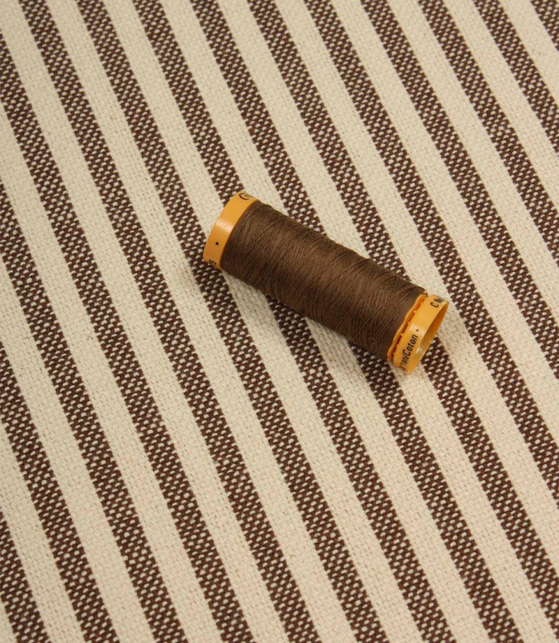 Broadway Stripe Mocha striped upholstery fabric with coordinating brown thread, highlighting the timeless vertical stripe design and woven texture.