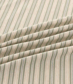 Close-up of Brookhaven Cascade striped fabric arranged in soft folds, showing sage green and muted blue vertical stripes, decorative dotted lines and textured weave.