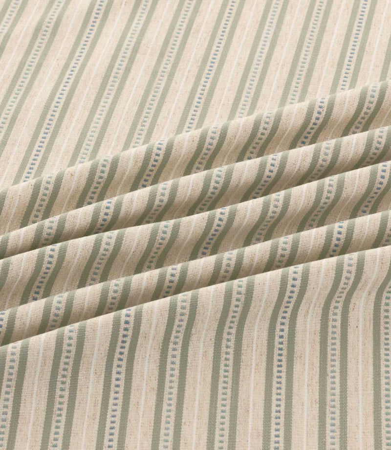 Close-up of Brookhaven Cascade striped fabric arranged in soft folds, showing sage green and muted blue vertical stripes, decorative dotted lines and textured weave.