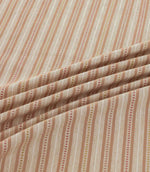 Brookhaven Coralee fabric draped in gentle folds, highlighting its coral, terracotta and mustard striped design, dotted detailing and textured surface.