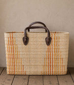 Woven basket tote bag with orange stripes and brown leather handles
