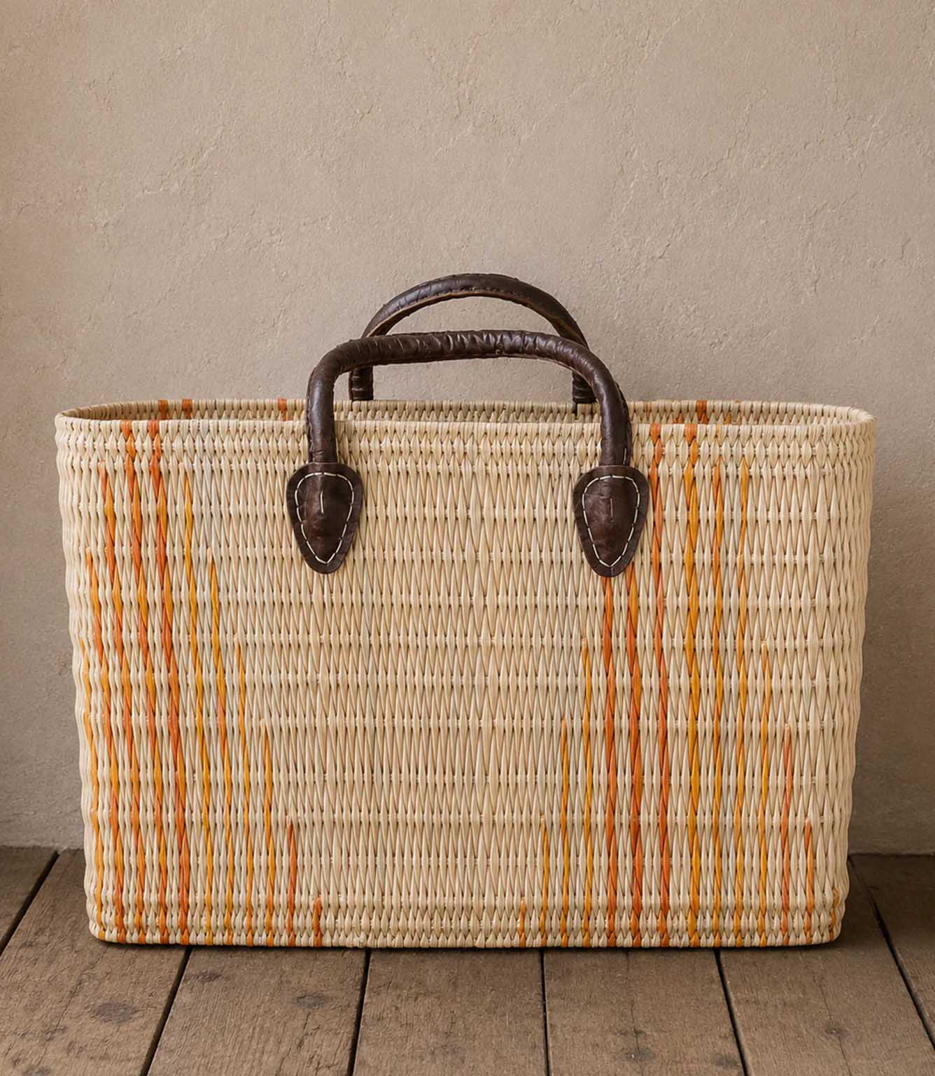 Woven basket tote bag with orange stripes and brown leather handles