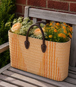 Woven basket tote bag with orange stripes and brown leather handles