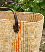 Woven basket tote bag with orange stripes and brown leather handles