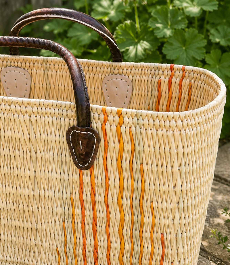 Woven basket tote bag with orange stripes and brown leather handles