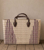 Woven basket tote bag with purple stripes and brown leather handles