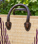 Woven basket tote bag with purple stripes and brown leather handles