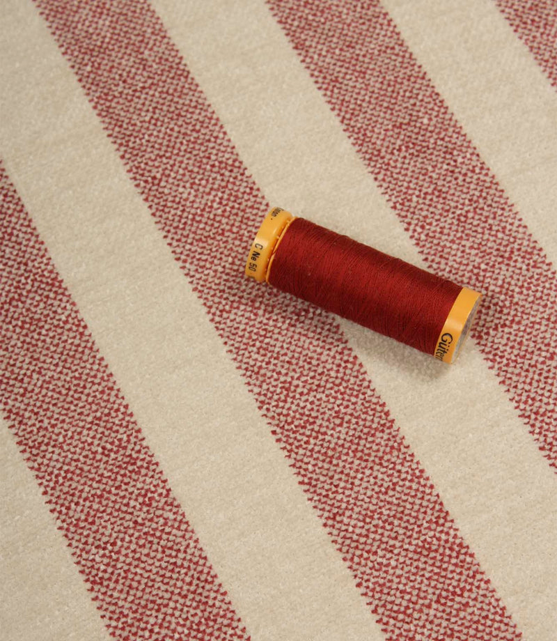 Burleigh Stripe Rose upholstery fabric with coordinating rose pink thread, highlighting the fire retardant striped weave and textured surface.
