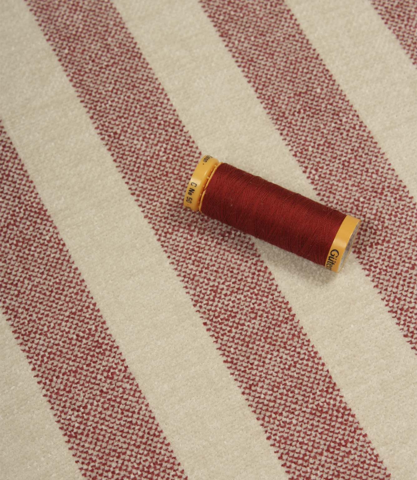 Burleigh Stripe Rose upholstery fabric with coordinating rose pink thread, highlighting the fire retardant striped weave and textured surface.
