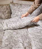 Voyage Maison Cademuir Reversible Muslin Duvet Cover Set in Nut being turned back to show its soft, relaxed texture and reversible bedding design.
