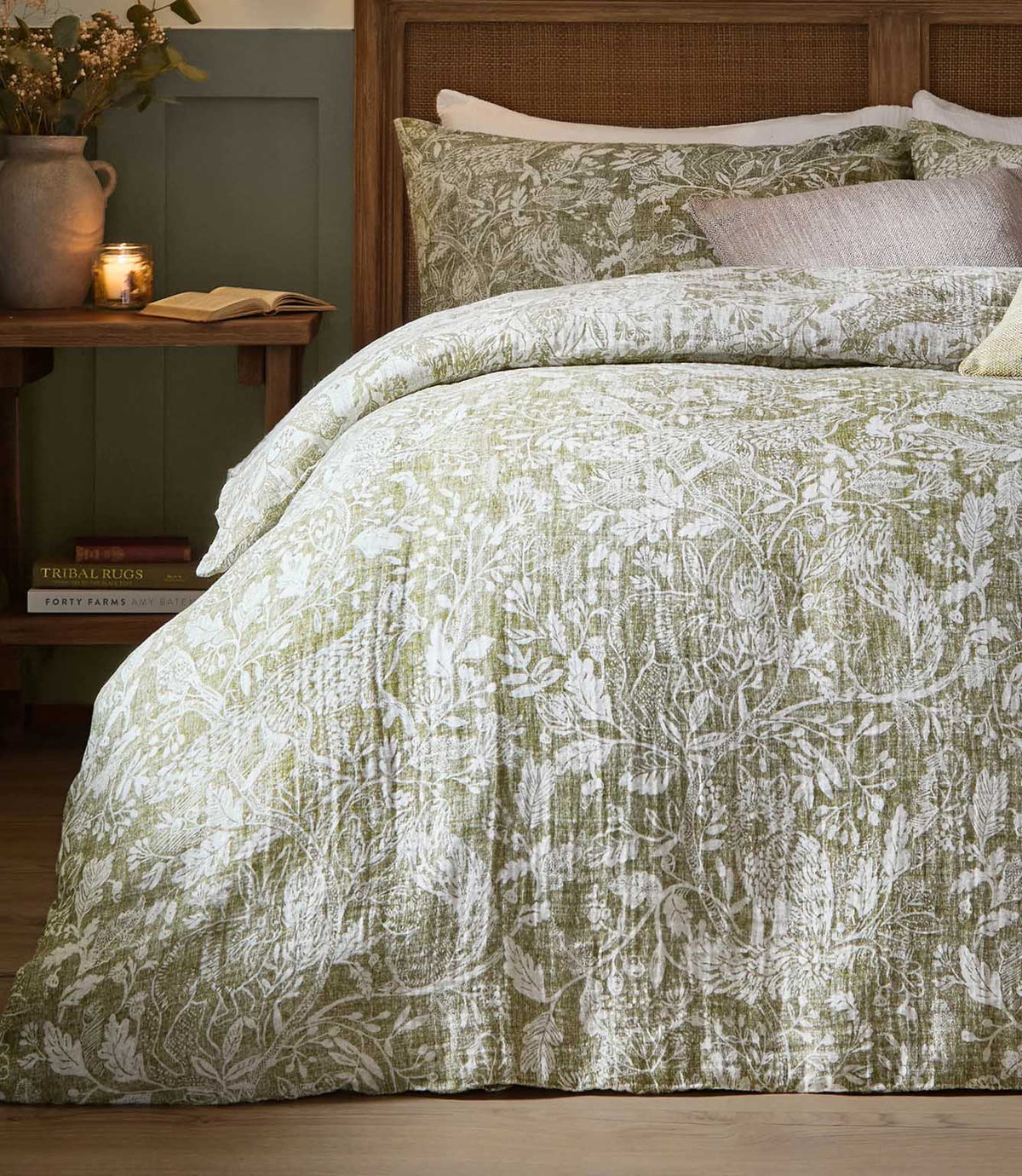 Voyage Maison Cademuir duvet cover set in green, featuring an intricate botanical and bird design with matching pillowcases on a wooden bed.