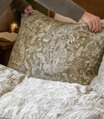 Close-up of a Cademuir pillowcase by Voyage Maison in green and white, showing the detailed bird and foliage pattern and softly textured finish.