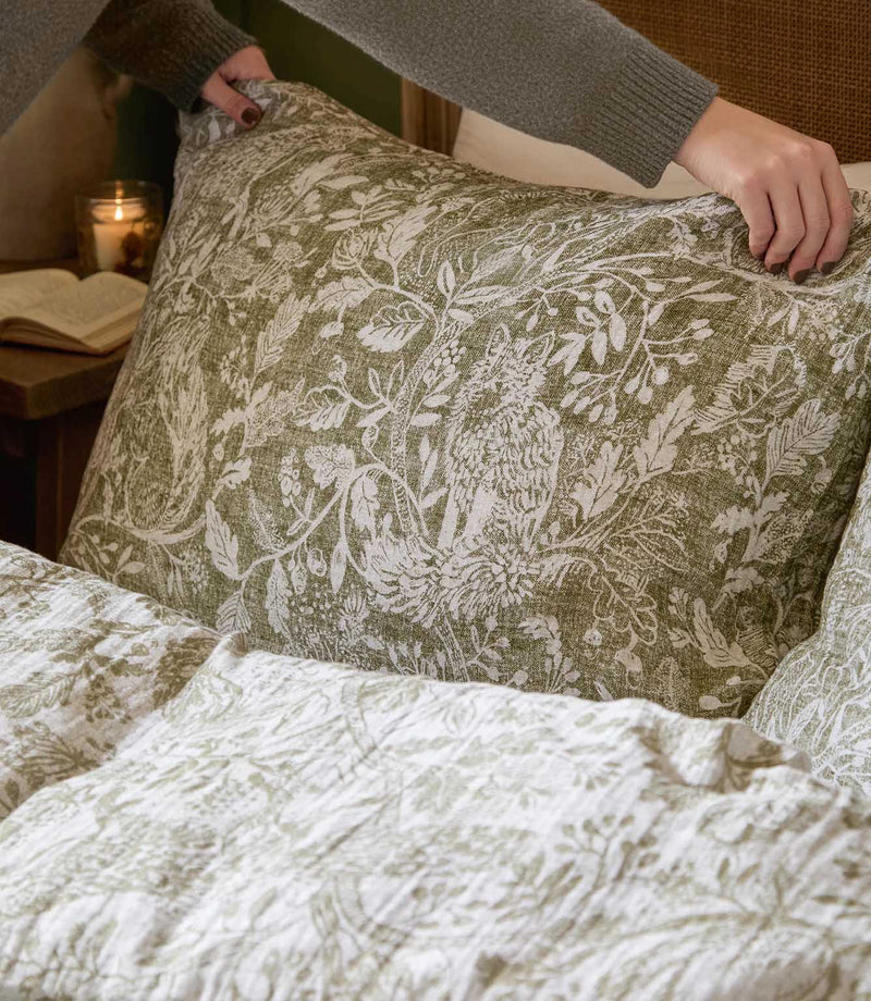 Close-up of a Cademuir pillowcase by Voyage Maison in green and white, showing the detailed bird and foliage pattern and softly textured finish.