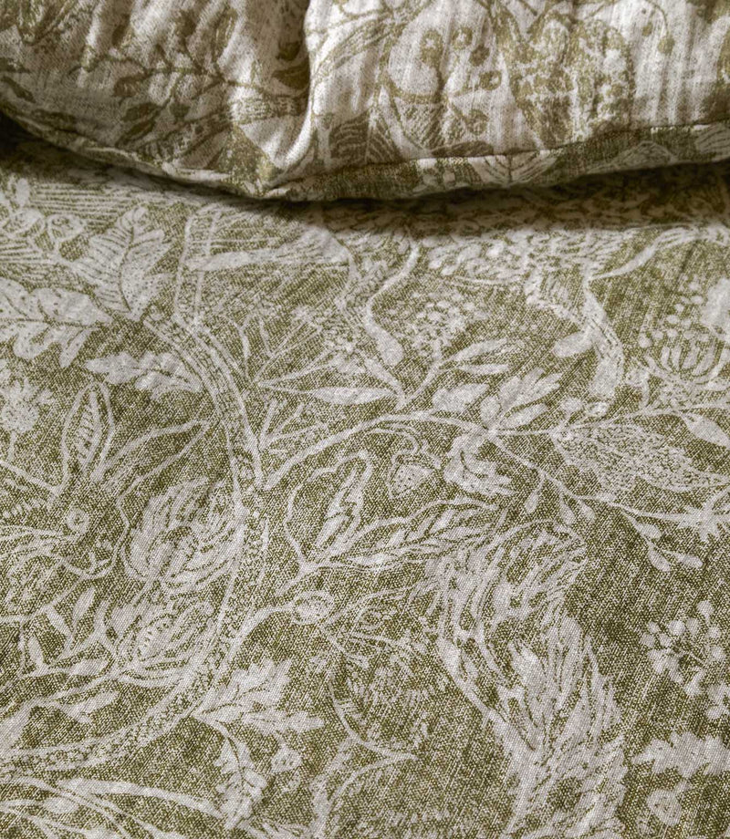 Detailed close-up of Voyage Maison Cademuir bedding in green and white, highlighting the intricate woodland design of birds, leaves and botanical motifs.