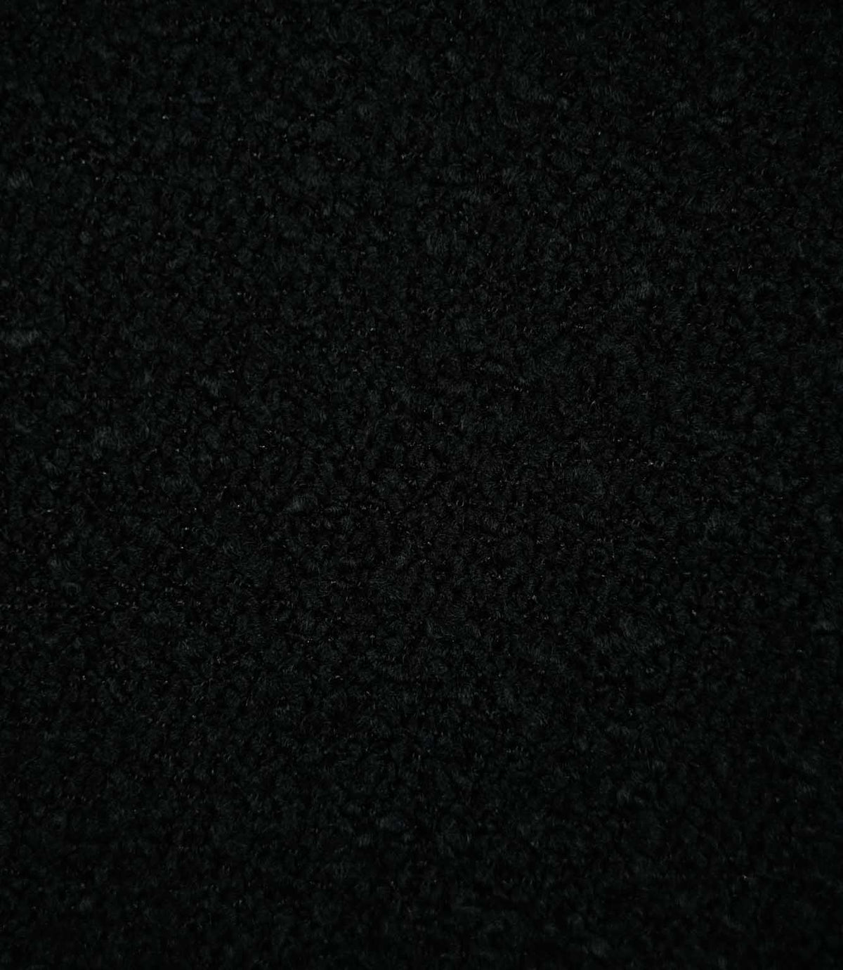 Close-up of Case Bouclé Noir upholstery fabric in deep black, showing its dense looped bouclé weave and richly textured surface.