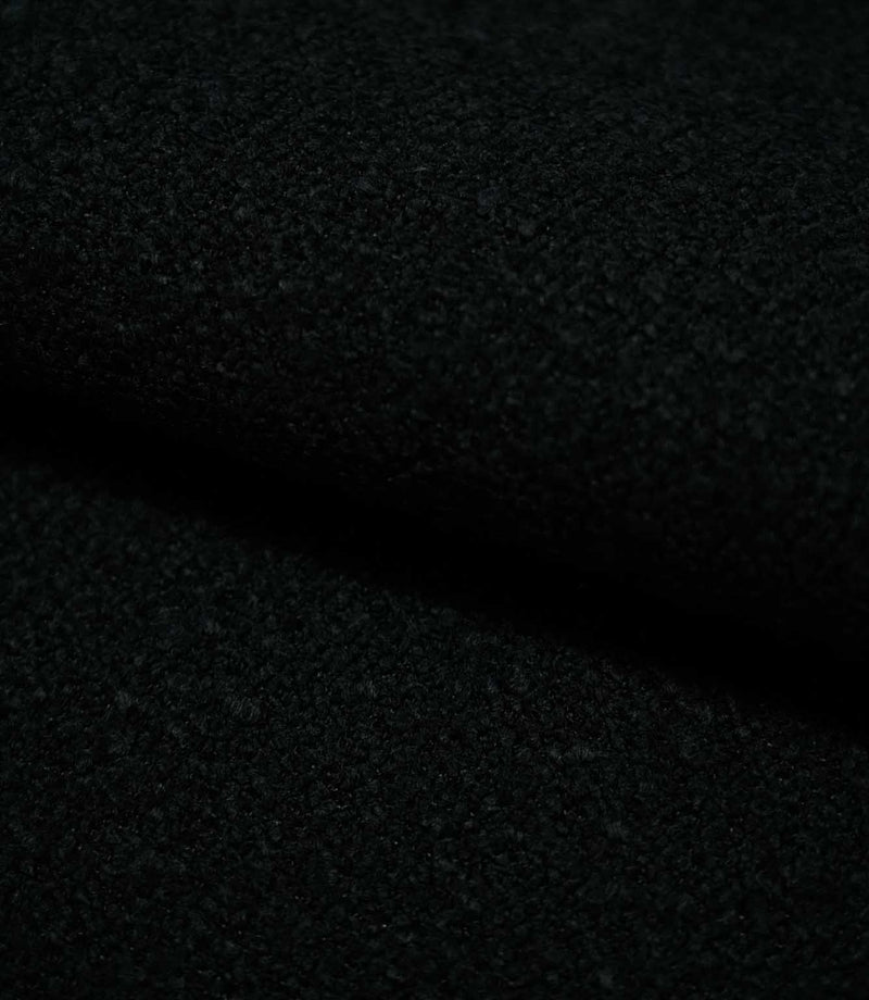 Close-up of folded Case Bouclé Noir fabric, showing the depth and tactile texture of the black bouclé upholstery material.