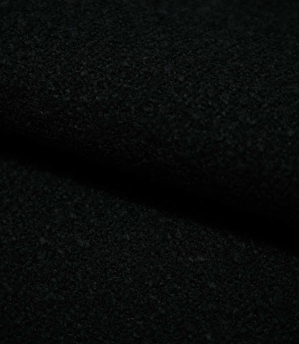 Close-up of folded Case Bouclé Noir fabric, showing the depth and tactile texture of the black bouclé upholstery material.