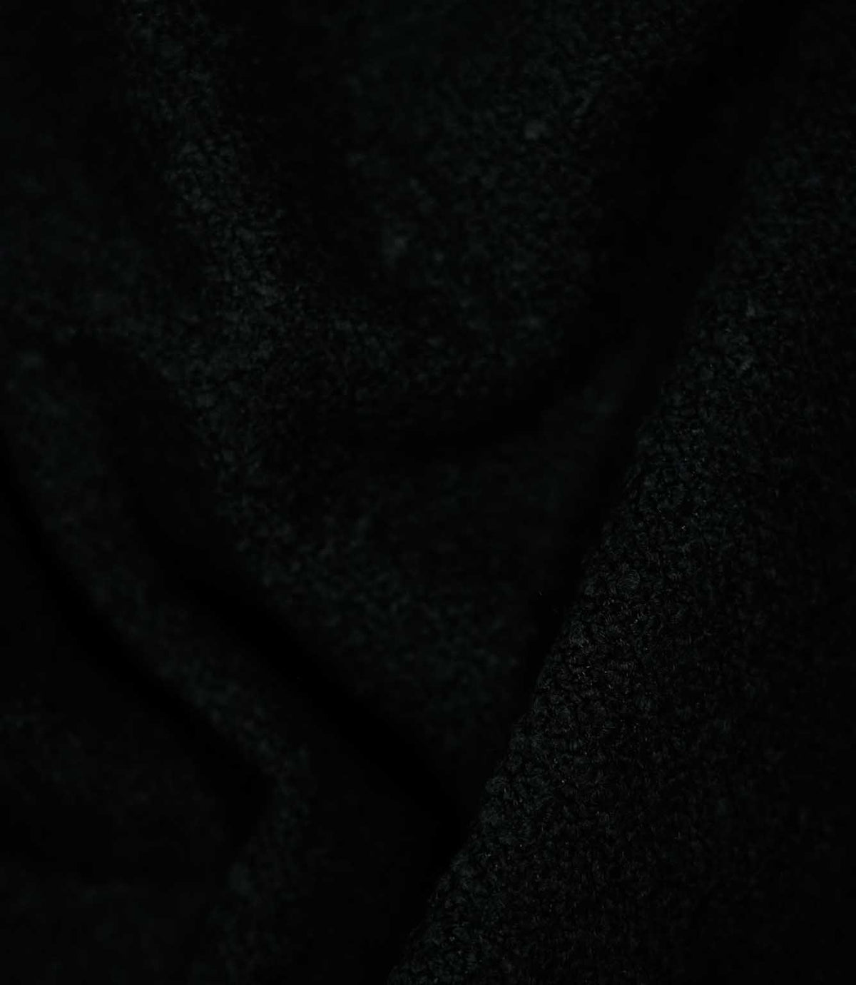 Case Bouclé Noir upholstery fabric draped into soft folds, showcasing its black colour, flexible handle and tactile looped texture.
