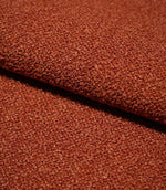 Close-up of folded Case Bouclé terracotta fabric, showing the substantial upholstery weight, dense looped texture and softly structured drape.