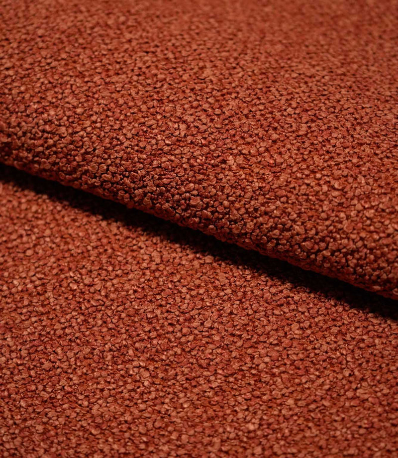 Close-up of folded Case Bouclé terracotta fabric, showing the substantial upholstery weight, dense looped texture and softly structured drape.