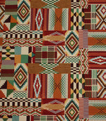 Multicoloured Southwestern-inspired upholstery fabric featuring patchwork geometric motifs in red, teal, green, ochre, black, and cream tones.