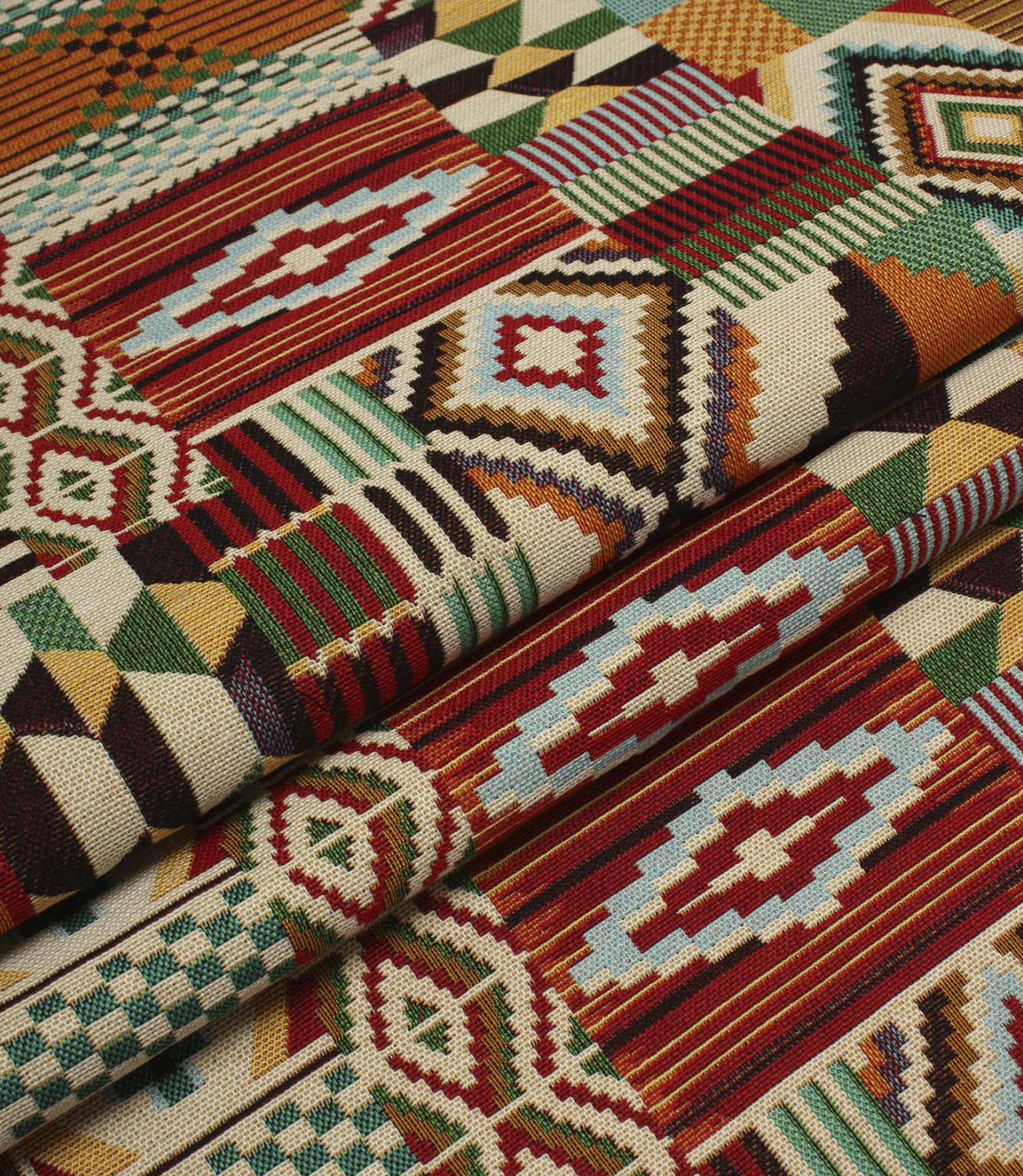 Folded Southwestern-style fabric displaying the structured drape and colourful geometric tapestry pattern in rich red, teal, ochre, and cream shades.