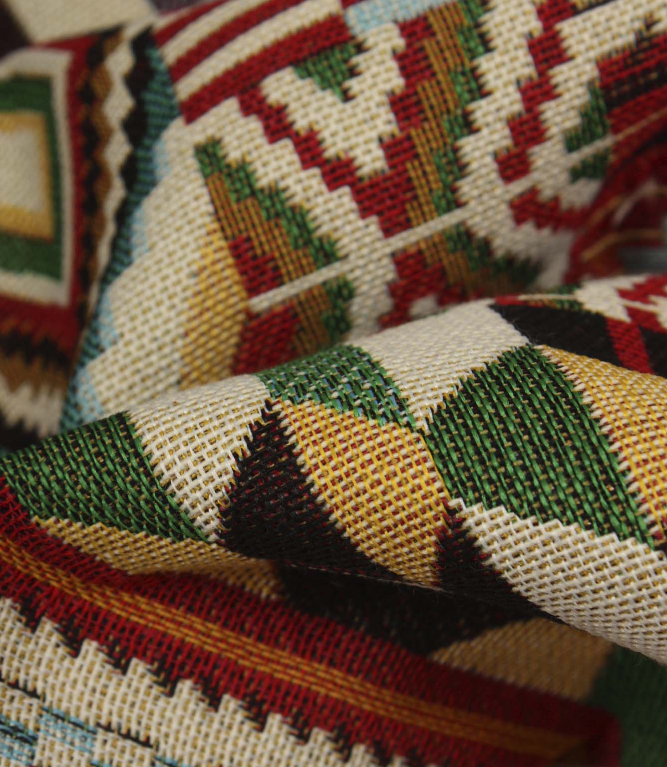 Detailed close-up of Southwestern-inspired woven upholstery fabric featuring textured geometric patterns in red, green, teal, black, and cream tones.