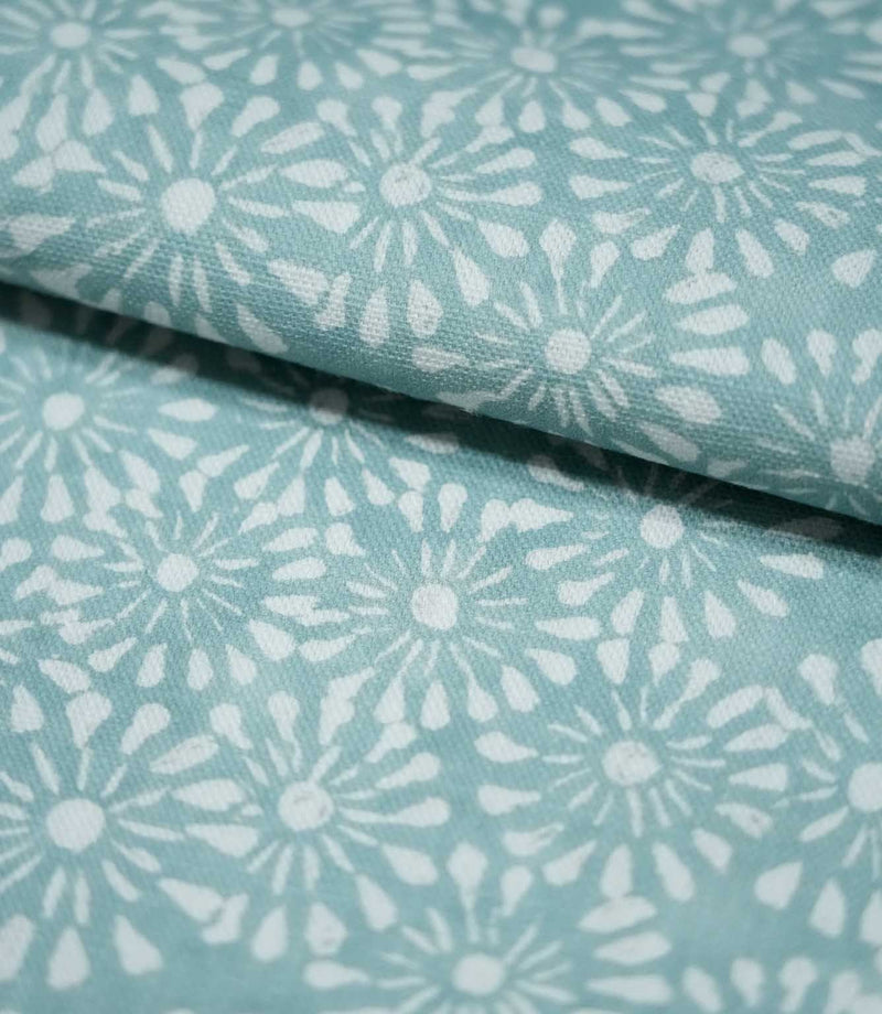 Close-up of Chamberry Duck Egg fabric folded over itself, showing the delicate white daisy-like floral pattern, muted duck egg background and fine woven texture.