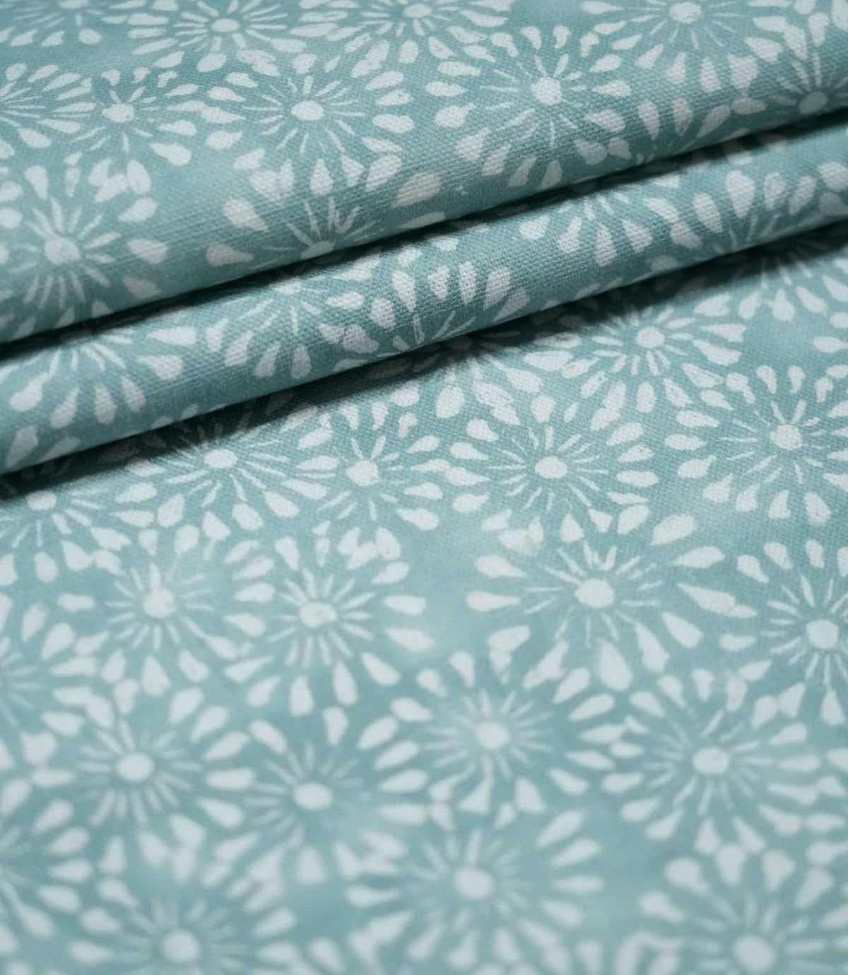 Chamberry Duck Egg floral fabric arranged in overlapping folds, highlighting the repeating white flower motifs, soft blue-green background and lightly textured woven finish.