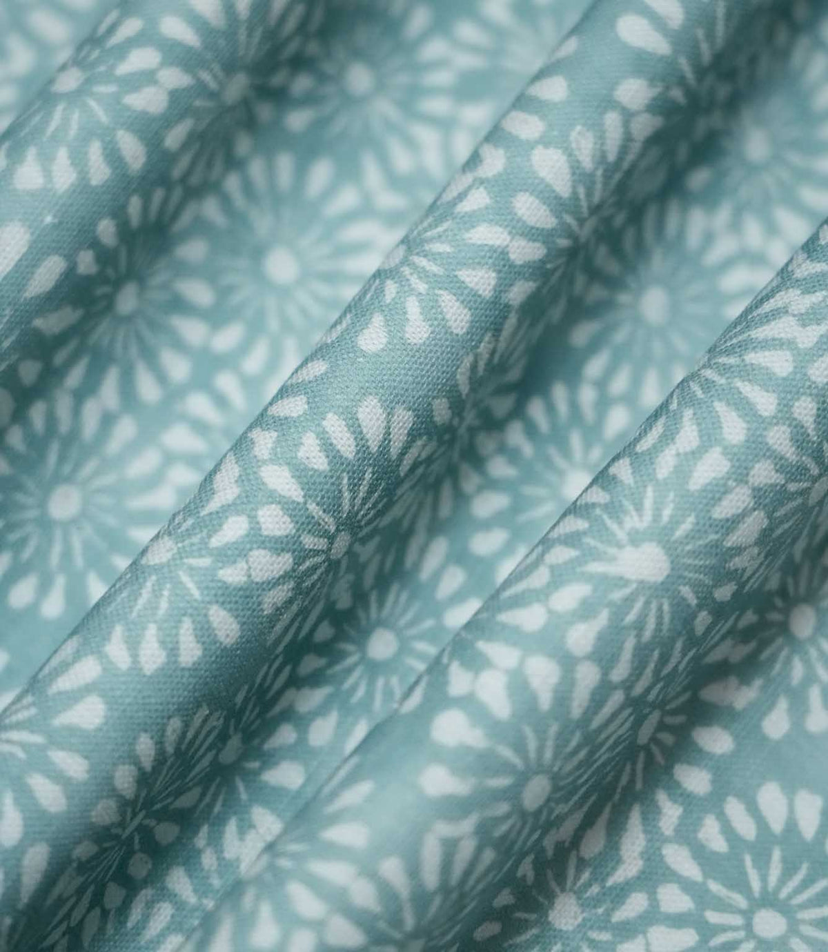 Chamberry Duck Egg fabric gathered into soft, flowing folds, displaying the small-scale white daisy-inspired floral pattern against a muted duck egg background and showing how the fabric drapes.