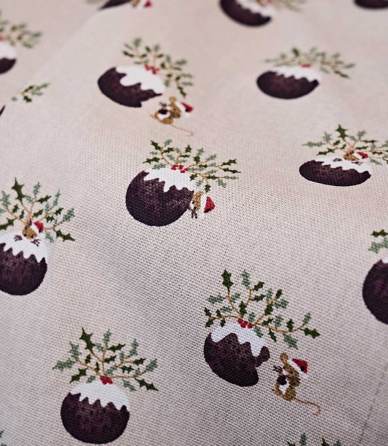 A close-up of a fabric pattern featuring Christmas pudding illustrations with holly, mice and mistletoe on a light beige textured background.