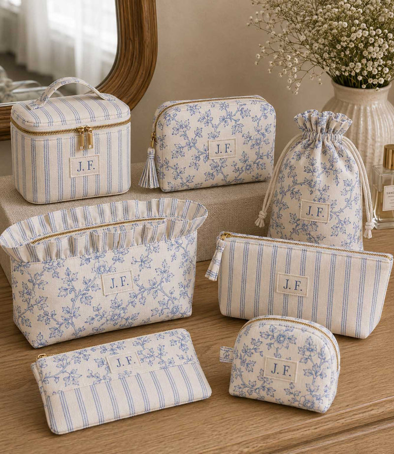 Set of blue ditsy floral and stripe fabric  makeup bags and pouches on a wooden cabinet