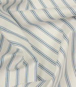 Draped striped fabric with soft blue vertical lines flowing across a natural ivory background.