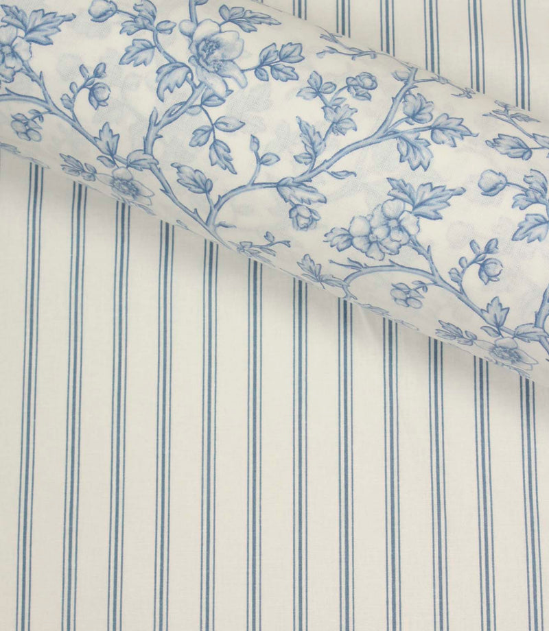 Coordinating blue floral fabric layered over a traditional blue ticking stripe fabric with an ivory background and fine vertical lines.