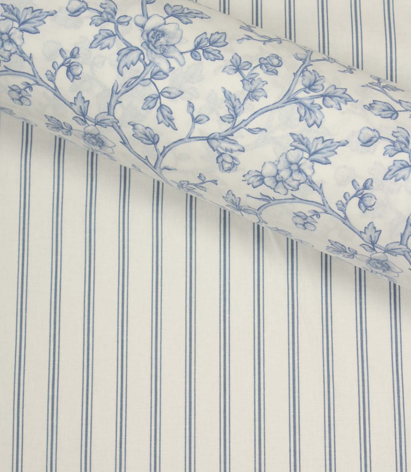 Coordinating blue floral fabric layered over a traditional blue ticking stripe fabric with an ivory background and fine vertical lines.