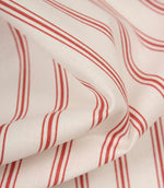 Detailed close-up of red striped fabric revealing the fine weave, soft handle, and timeless ticking stripe pattern.