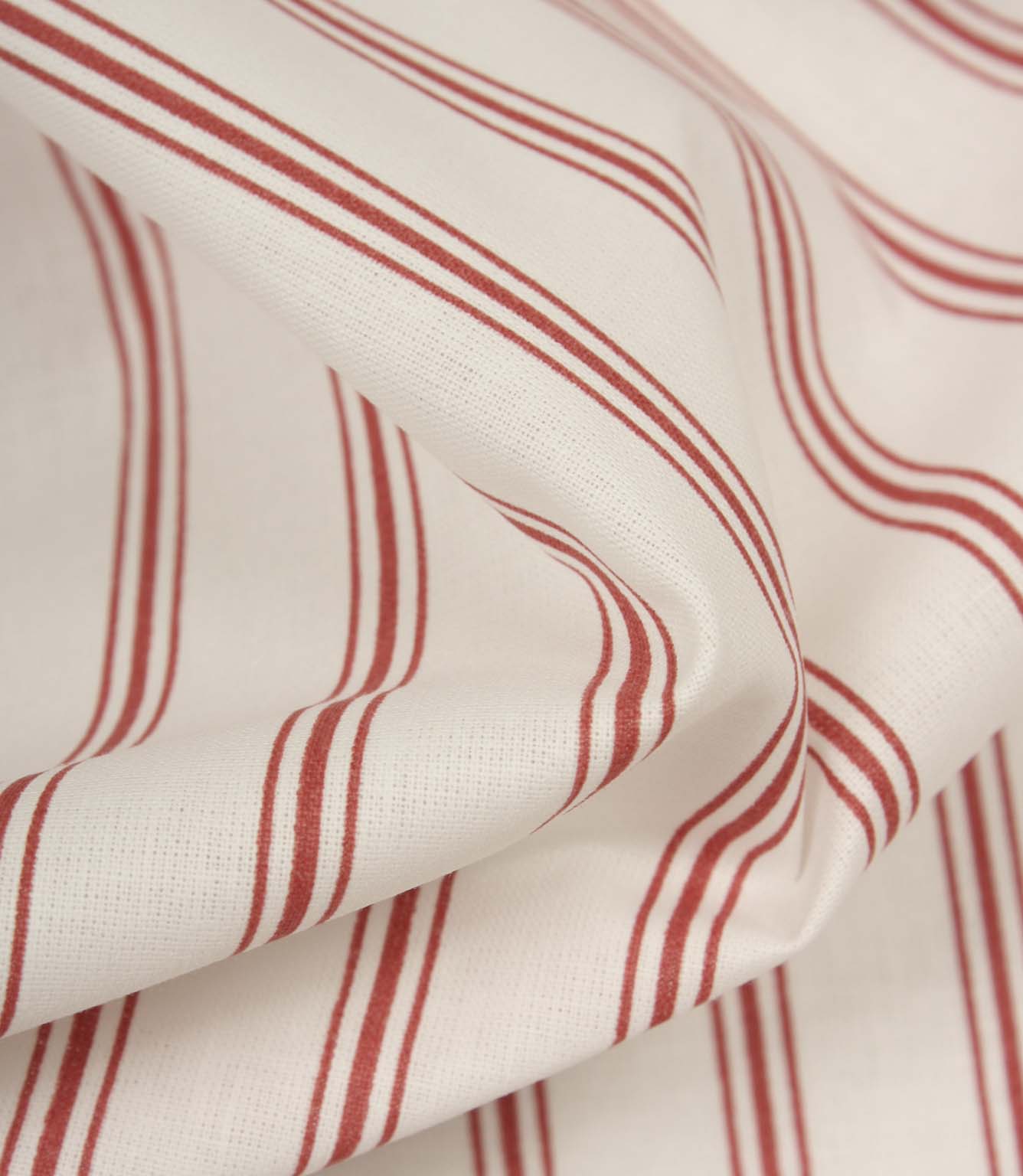 Detailed close-up of red striped fabric revealing the fine weave, soft handle, and timeless ticking stripe pattern.