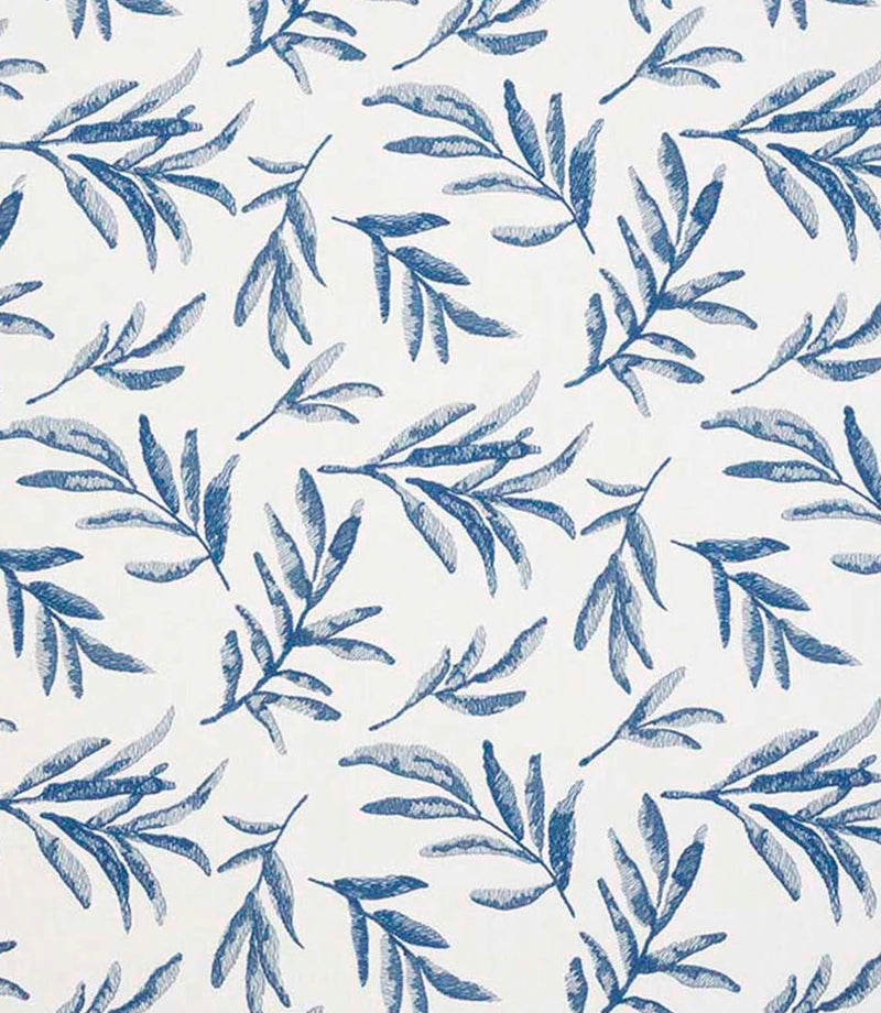 Close-up of embroidered floral upholstery fabric showing detailed leaf motifs in layered blue tones on a neutral base.