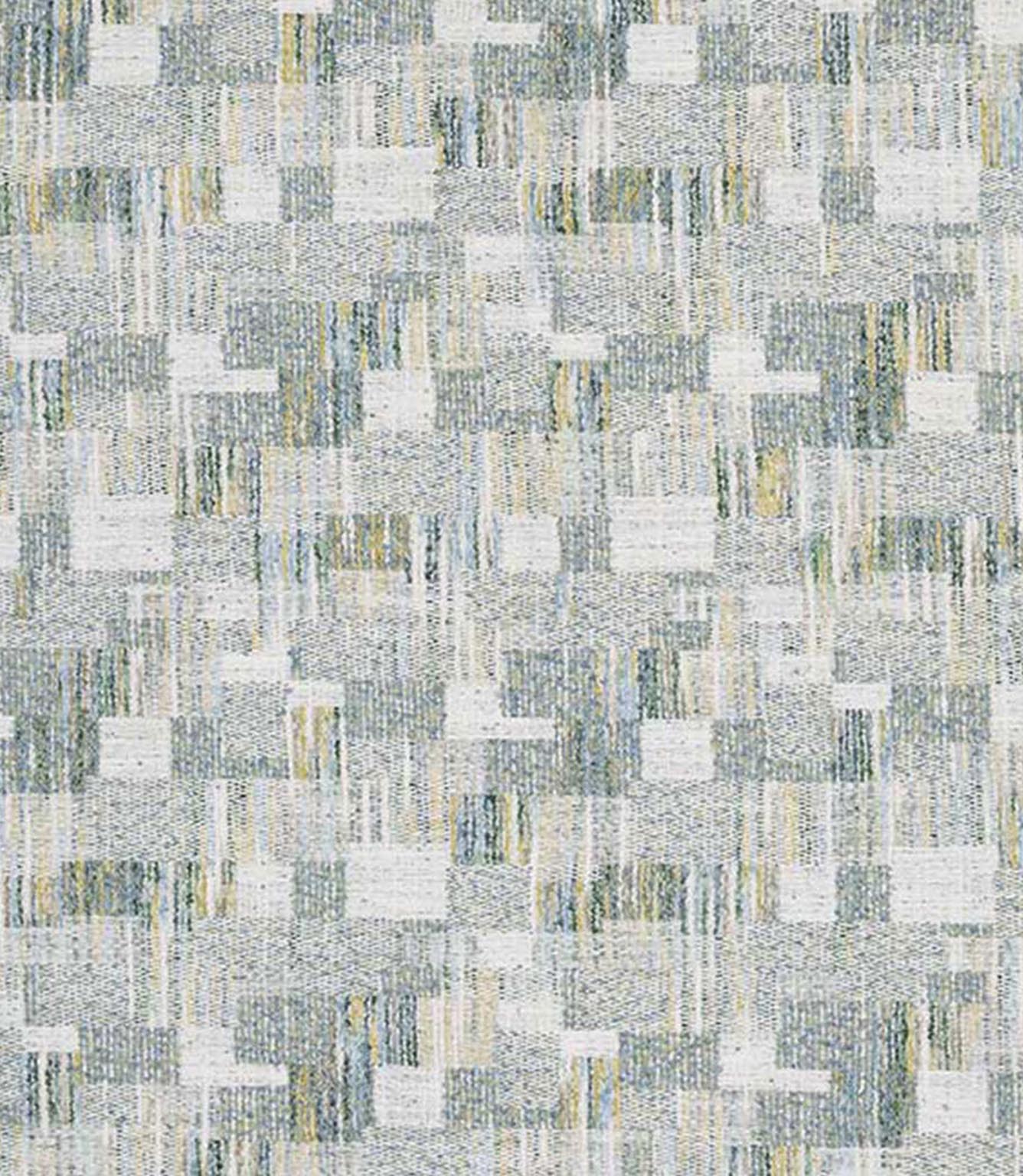 Close-up of woven geometric fabric with an abstract check pattern in soft sage green, pale blue and warm neutral tones, featuring a textured, layered weave.