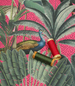 Tropical animal upholstery fabric with lush green botanical leaves, a peacock motif and vibrant pink background with coordinating thread spools.
