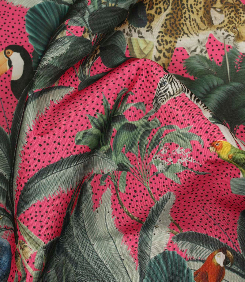 Draped tropical print fabric showcasing leopards, parrots, zebras and layered palm leaves on a bold pink spotted design.