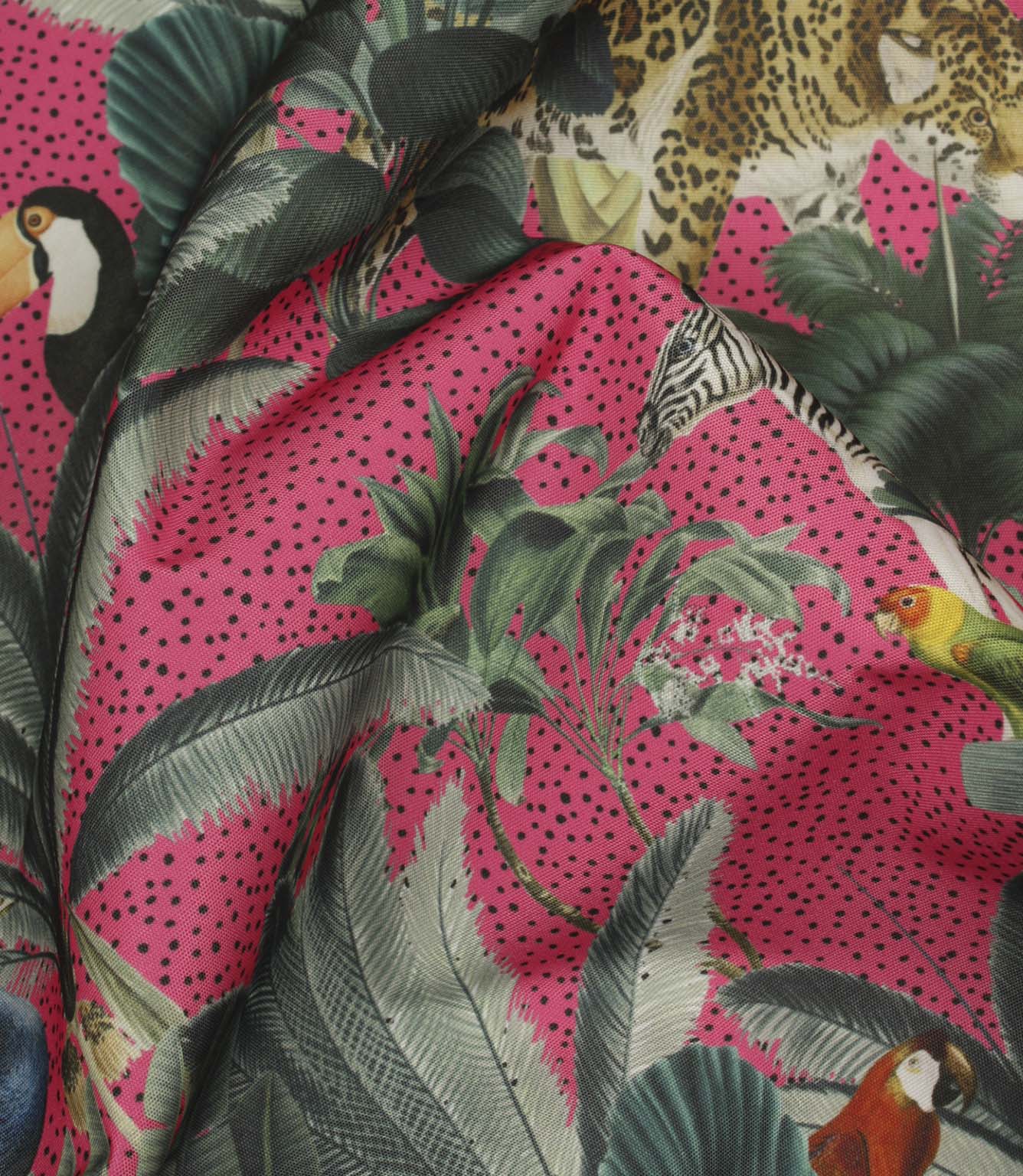 Draped tropical print fabric showcasing leopards, parrots, zebras and layered palm leaves on a bold pink spotted design.