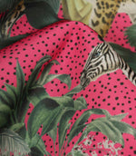 Close-up of tropical jungle fabric highlighting the textured weave, vivid pink background, black speckled detailing and exotic botanical print.