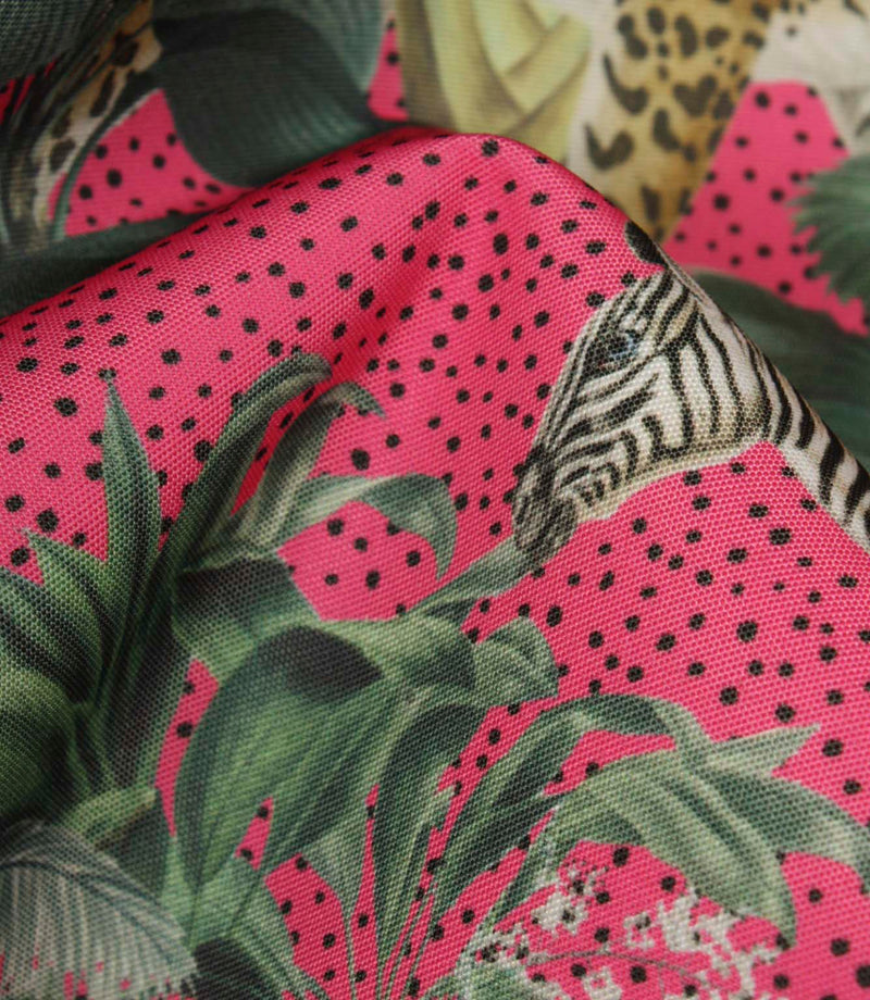 Close-up of tropical jungle fabric highlighting the textured weave, vivid pink background, black speckled detailing and exotic botanical print.